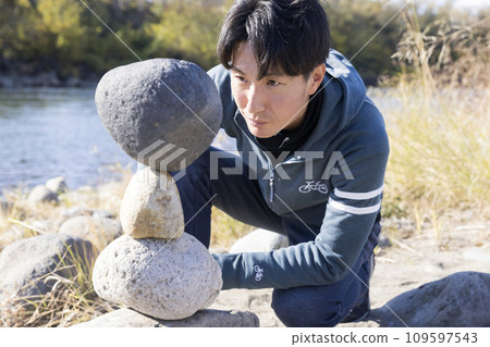 A man checking completed rock balancing A man checking completed rock balancing 109597543