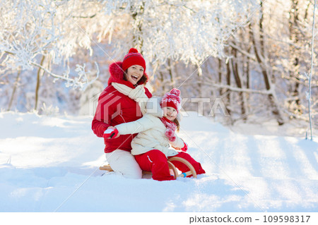 Mother and child sledding. Winter snow fun. Family on sleigh. 109598317