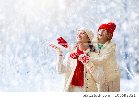 Mother and child in knitted winter hats in snow. Mother and child in knitted winter hats in snow. 109598321