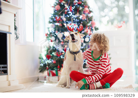 Christmas at home. Kids and dog under Xmas tree. Christmas at home. Kids and dog under Xmas tree. 109598329