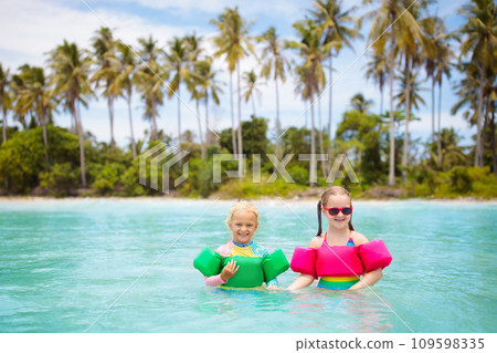 Kids on tropical beach. Swim aids for children. Kids on tropical beach. Swim aids for children. 109598335
