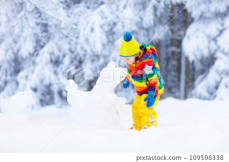Child making snowman. Kids play in snow in winter Child making snowman. Kids play in snow in winter 109598338