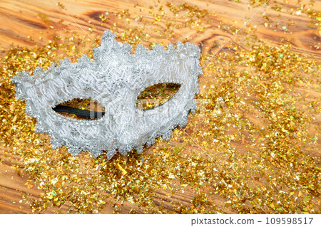 silver Venetian mask on a golden shiny background. New Year's masquerade silver Venetian mask on a golden shiny background. New Year's masquerade 109598517