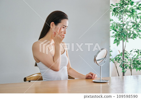 A woman in her 30s worries about wrinkles on her skin while looking in the mirror A woman in her 30s worries about wrinkles on her skin while looking in the mirror 109598590