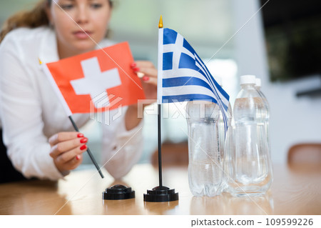 Young female secretary preparing room for international negotiations between greece and switzerland 109599226