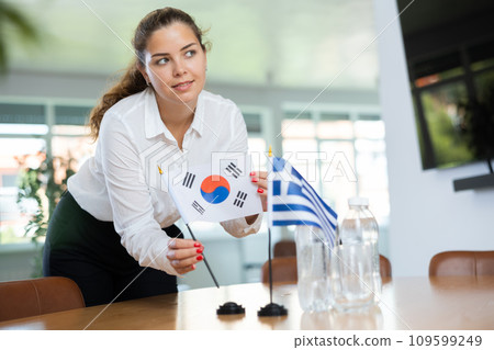 Young female secretary preparing room for international negotiations between greece and south korea 109599249