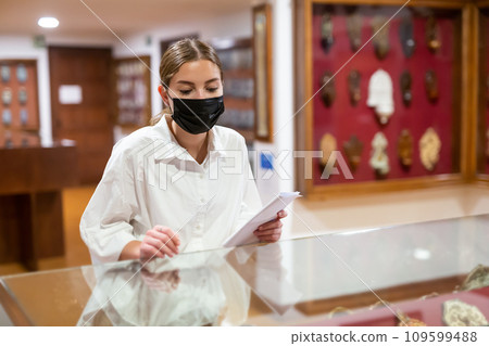Young woman in mask with booklet visiting archaeological museum 109599488
