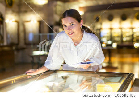 Young girl in the museum looks at the exposition behind glass case Young girl in the museum looks at the exposition behind glass case 109599493