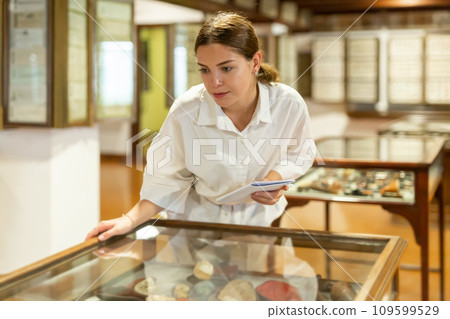 Young girl in the museum looks at the exposition behind glass case Young girl in the museum looks at the exposition behind glass case 109599529
