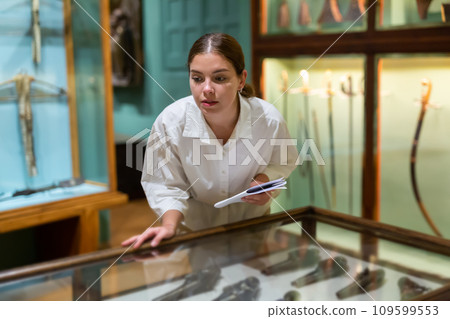 Woman looking at exhibits in glazed stands in museum 109599553