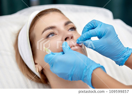 cosmetologist makes injections to enlarge the lips of beautiful woman. beauty injections. 109599857