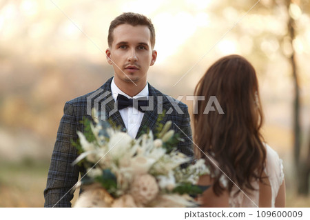 portrait of bride in white wedding dress and groom standing outdoor on natural background portrait of bride in white wedding dress and groom standing outdoor on natural background 109600009