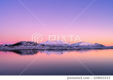 Snowy mountains, sea bay, reflection in water at sunset in winter 109601015