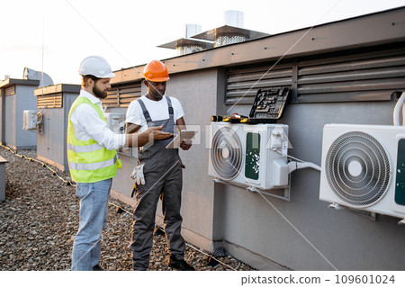Multicultural males repairing air conditioner using tablet Multicultural males repairing air conditioner using tablet 109601024