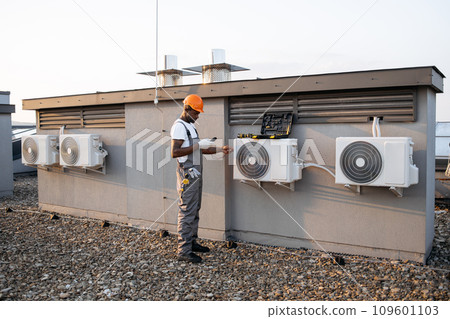 Black man checking air conditioner with digital multimeter Black man checking air conditioner with digital multimeter 109601103