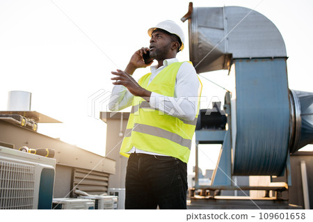Man engineer standing and talking on smartphone on roof Man engineer standing and talking on smartphone on roof 109601658