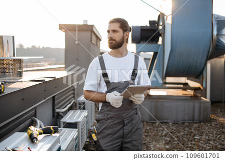 Construction man using tablet while working on rooftop 109601701