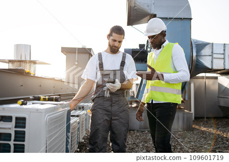 Men workers measuring voltage of conditioner on factory 109601719