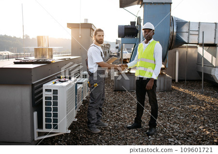 Males engineers standing and shaking hands on roof Males engineers standing and shaking hands on roof 109601721