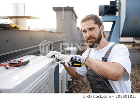 Repairman fixing conditioner using screwdriver on roof Repairman fixing conditioner using screwdriver on roof 109601813