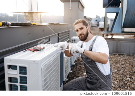Man builder repairing conditioner using screwdriver outdoor Man builder repairing conditioner using screwdriver outdoor 109601816
