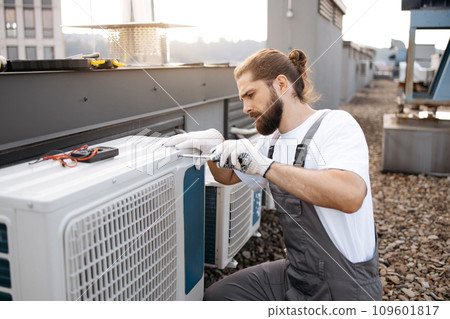 Man builder repairing conditioner using screwdriver outdoor Man builder repairing conditioner using screwdriver outdoor 109601817