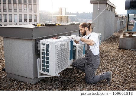 Man builder repairing conditioner using screwdriver outdoor Man builder repairing conditioner using screwdriver outdoor 109601818