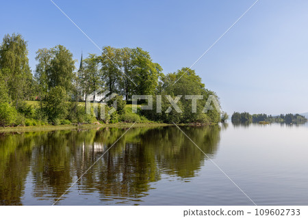 Summer view of Kvam Church in Nord-Fron Norway through trees by Snasavatnet lake 109602733