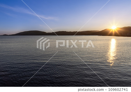 Midnight sun casting golden rays on fjord near Bodo port under clear sky in Lofoten Islands Norway Midnight sun casting golden rays on fjord near Bodo port under clear sky in Lofoten Islands Norway 109602741