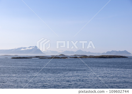 Summer tableau from ferry to Lofoten Island with tranquil North Sea and snow-capped mountains 109602744