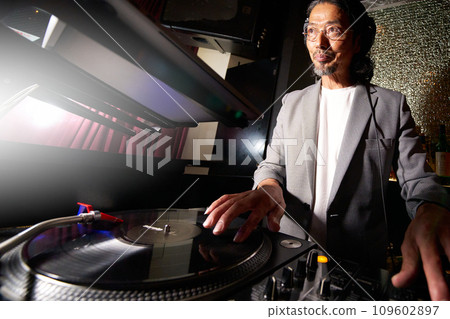 Male DJ playing music on turntables 109602897