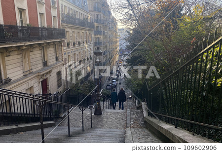 Montmartre, the highest hill in Paris. Passersby descending the Montmartre stairs near Place Louise Michel (rear view) 109602906