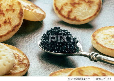 Silver spoon with caviar closeup with blinis, an elegant festive appetizer 109603053
