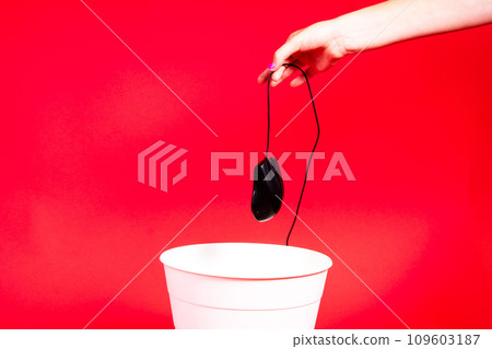 A computer mouse with a wire is thrown into the office wastebasket. 109603187