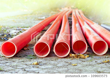 Red plastic communication water pipes on a construction site in sunlight 109603573
