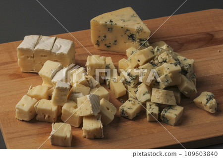 Pieces of cheese assorted on a wooden board Pieces of cheese assorted on a wooden board 109603840