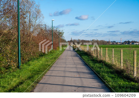 Londerzeel, Belgium - Asphalt biking path along the railway track through the Flemish countryside Londerzeel, Belgium - Asphalt biking path along the railway track through the Flemish countryside 109604209
