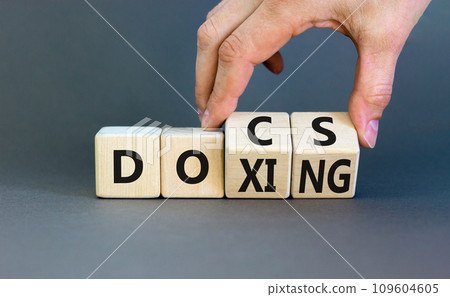 Docs or doxing symbol. Concept words Docs Doxing on wooden block. Beautiful grey table grey background. Businessman hand. Business docs or doxing concept. Copy space. Docs or doxing symbol. Concept words Docs Doxing on wooden block. Beautiful grey table grey background. Businessman hand. Business docs or doxing concept. Copy space. 109604605