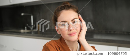 Portrait of gorgeous young woman in glasses, with happy smile, looking cute and tender, concept of modern people lifestyle Portrait of gorgeous young woman in glasses, with happy smile, looking cute and tender, concept of modern people lifestyle 109604795
