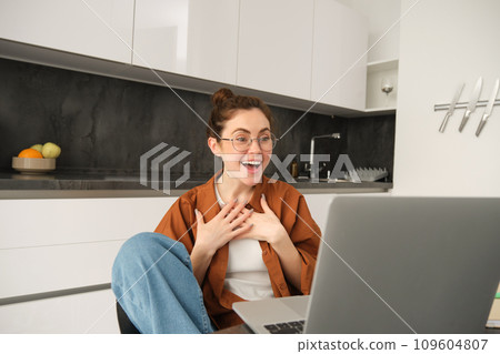 Portrait of young woman working from home, sitting at home with laptop, talking with friend on computer, online chatting, connects to video conversation 109604807