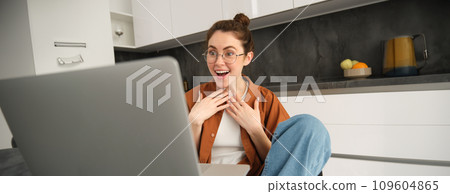 Work from home, remote job concept. Young woman sitting in kitchen, using laptop, joins video chat conversation, give online lessons, talking to client on computer Work from home, remote job concept. Young woman sitting in kitchen, using laptop, joins video chat conversation, give online lessons, talking to client on computer 109604865