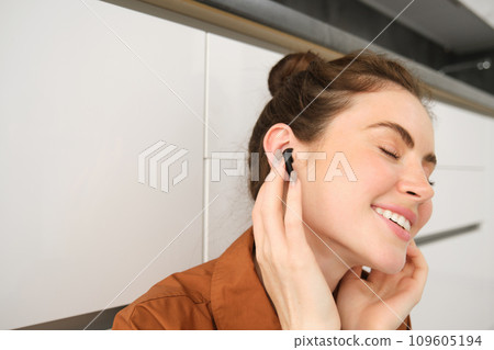 Close up portrait of woman smiling from sound quality in her wireless black earphones, listening to music in headphones, she has pleased face and eyes closed from satisfaction Close up portrait of woman smiling from sound quality in her wireless black earphones, listening to music in headphones, she has pleased face and eyes closed from satisfaction 109605194
