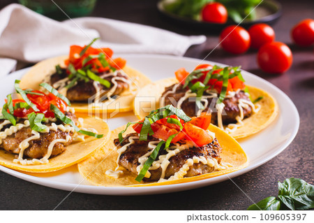 Smash Burger Tacos with tomatoes, sauce and herbs on a plate on the table 109605397