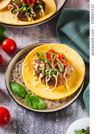 Smash Burger Tacos with beef patty, tomatoes and basil on a plate vertical view 109605410