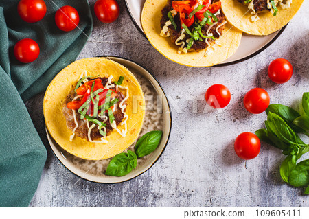 Smash Burger Tacos with beef patty, tomatoes and herbs on a plate top view Smash Burger Tacos with beef patty, tomatoes and herbs on a plate top view 109605411