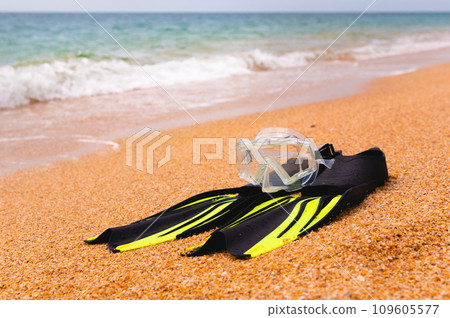 pair of fins and a diving mask on a sandy beach, bottom view. Space for text or advertising of a sports store or beach resort 109605577