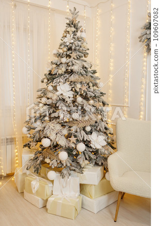 Christmas tree with in artificial snow, with festive decorations, white xmas glittering baubles, balls, shiny flower ornaments. Garland with gold lights Illuminate on backdrop. New year 2025 holidays. Christmas tree with in artificial snow, with festive decorations, white xmas glittering baubles, balls, shiny flower ornaments. Garland with gold lights Illuminate on backdrop. New year 2025 holidays. 109607082