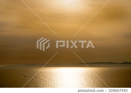 The sea and a small boat dyed by the setting sun The sea and a small boat dyed by the setting sun 109607495