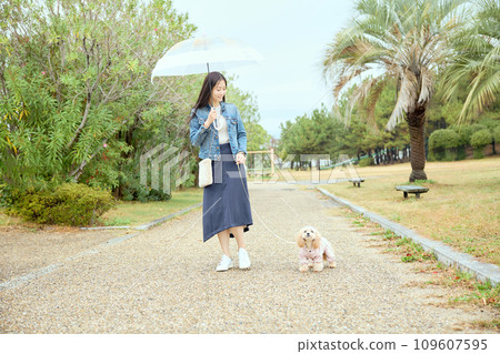 一個女人在雨中帶著她的狗在公園散步 一個女人在雨中帶著她的狗在公園散步 109607595
