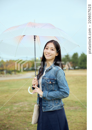 A woman walking with an umbrella in the park in the rain A woman walking with an umbrella in the park in the rain 109607628